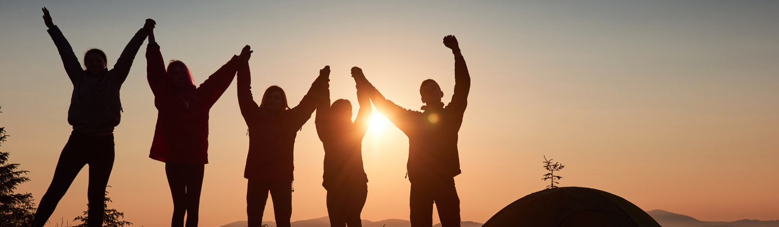 Silhueta de pessoas comemorando o dia do amigo ao pôr-do-sol
